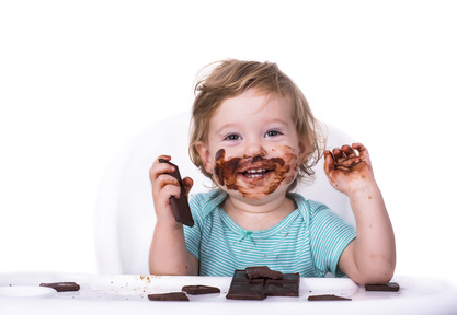 Adorable child eating chocolate with face covered in chocolate